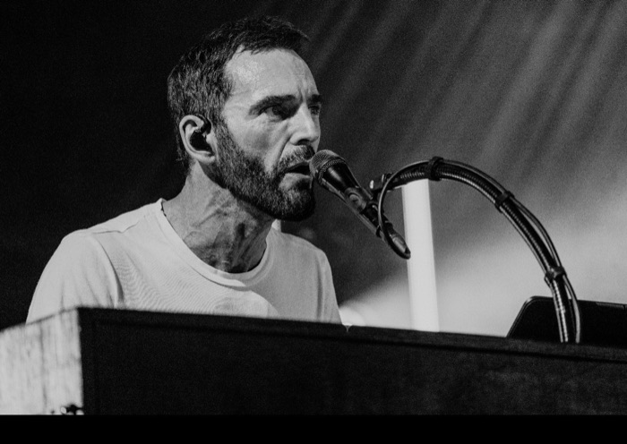 Black-and-white close-up of Johnny McDaid singing at the keyboard microphone